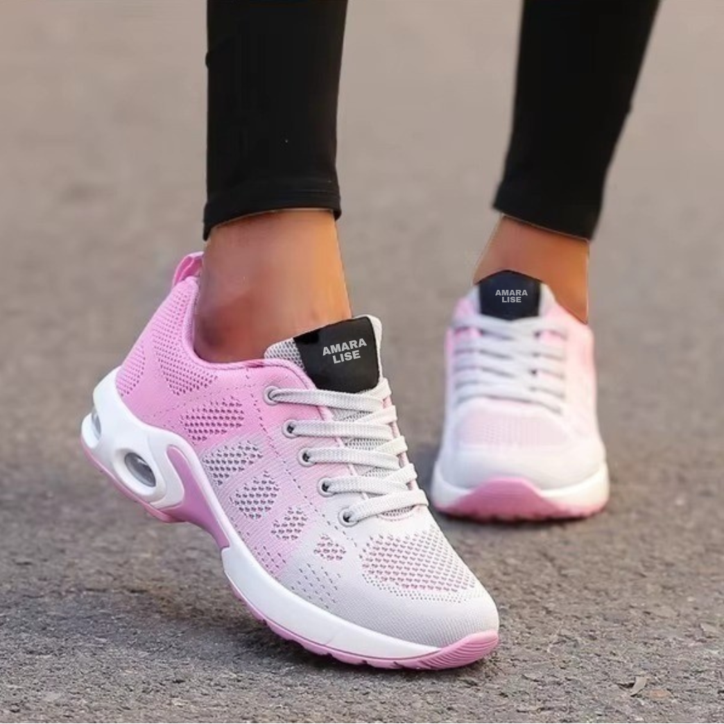 Women’s pink and white breathable knit trainers with cushioned air sole and white laces, worn with black leggings outdoors.