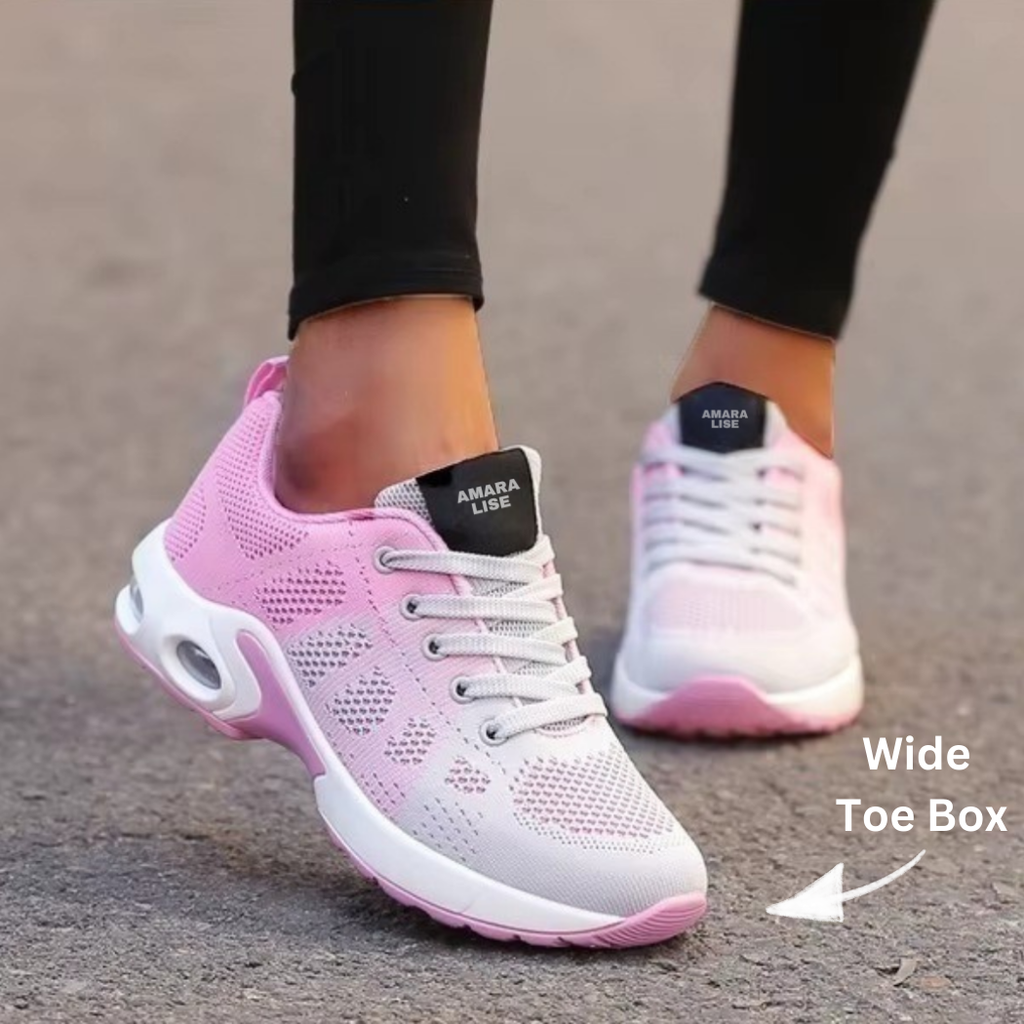 Women’s pink and white breathable knit trainers with cushioned air sole and white laces with wide toe box arrow, worn with black leggings outdoors.