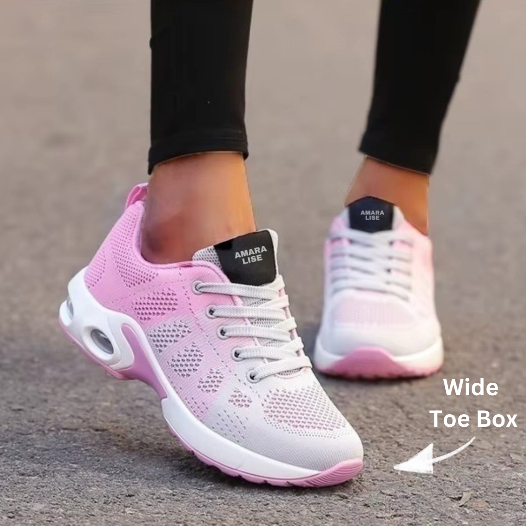 Women’s pink and white breathable knit trainers with cushioned air sole and white laces with wide toe box arrow, worn with black leggings outdoors.