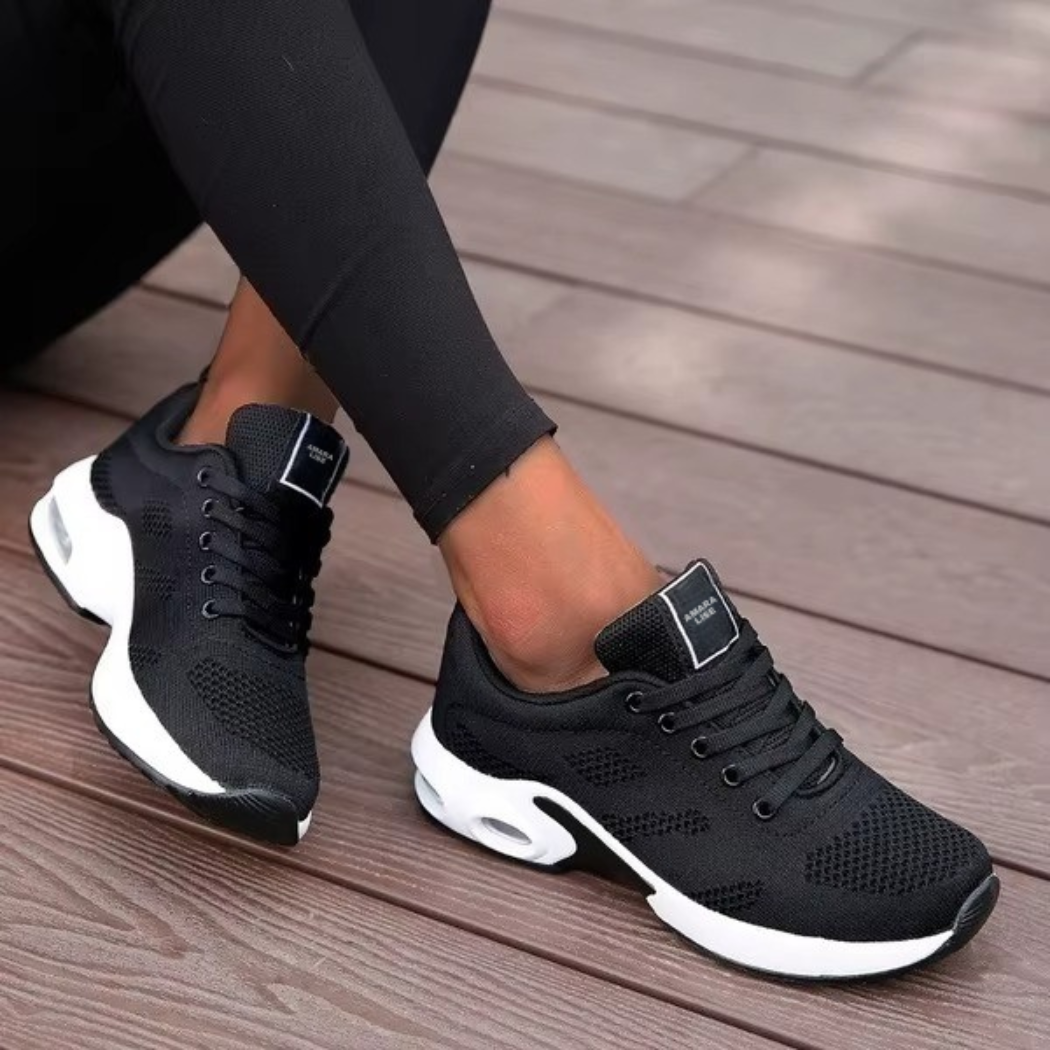 Women’s black mesh trainers with white cushioned sole and lace-up fastening, styled with black leggings.