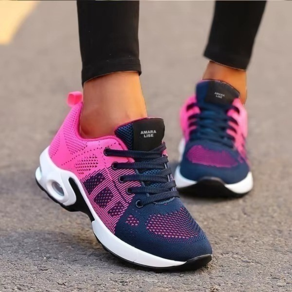 Women’s navy and pink lightweight mesh trainers with air cushion heel and lace-up design, styled with black leggings.